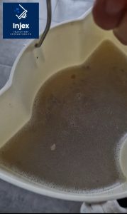 Eau usée brunâtre et mousse dans le bac de récupération après nettoyage d’un canapé à l’injecteur-extracteur.